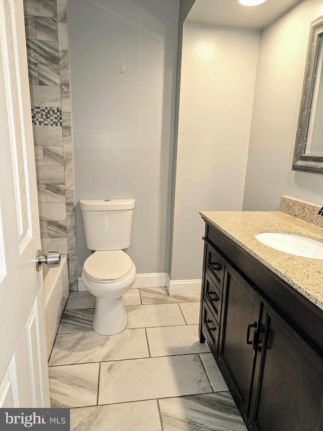 full bath with toilet, vanity, marble finish floor, and baseboards