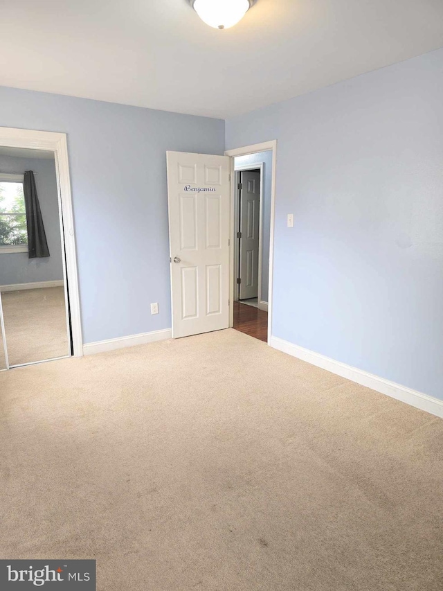 unfurnished bedroom with baseboards, carpet floors, and a closet