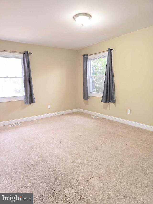 carpeted empty room with visible vents and baseboards