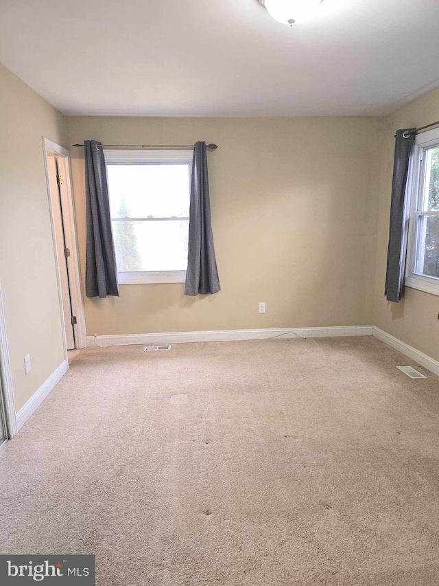 empty room featuring visible vents, carpet flooring, and baseboards