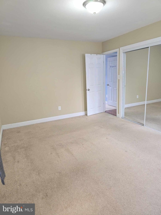 unfurnished bedroom featuring a closet, baseboards, and carpet floors