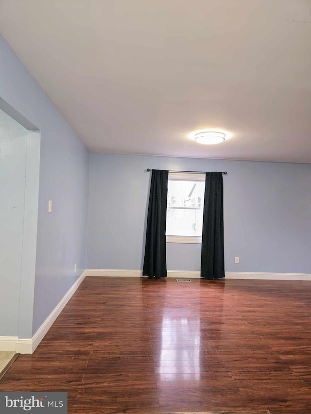 spare room featuring visible vents, baseboards, and wood finished floors