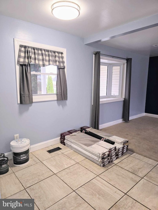 unfurnished bedroom featuring tile patterned floors, visible vents, baseboards, and carpet floors