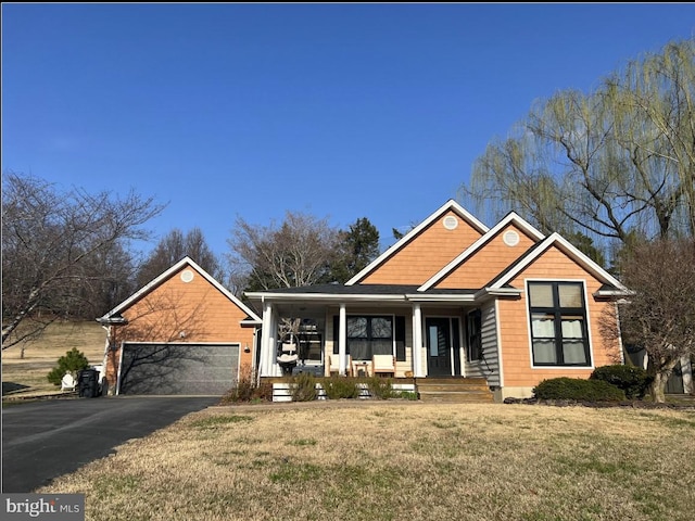 view of front of house with a front lawn, an attached garage, covered porch, and driveway