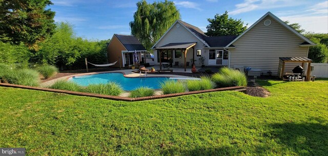 back of property with a patio area, a lawn, and an outdoor pool