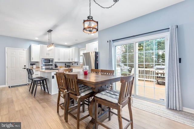 dining area with a notable chandelier, recessed lighting, light wood-type flooring, and baseboards