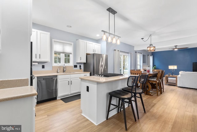 kitchen featuring a sink, stainless steel appliances, a kitchen breakfast bar, and white cabinetry