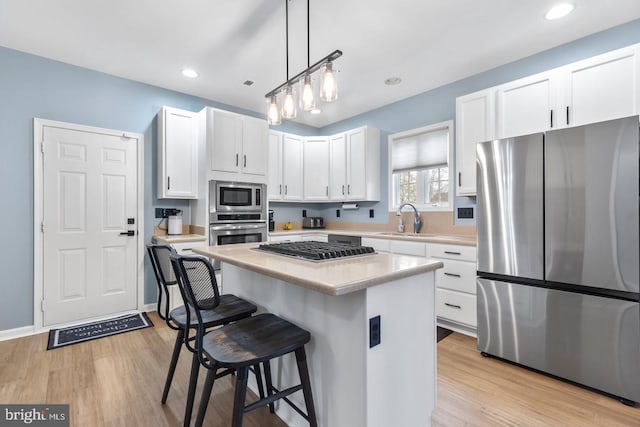 kitchen featuring white cabinets, stainless steel appliances, light countertops, and a sink