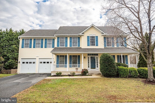 view of front of house featuring a front lawn, driveway, fence, covered porch, and a garage