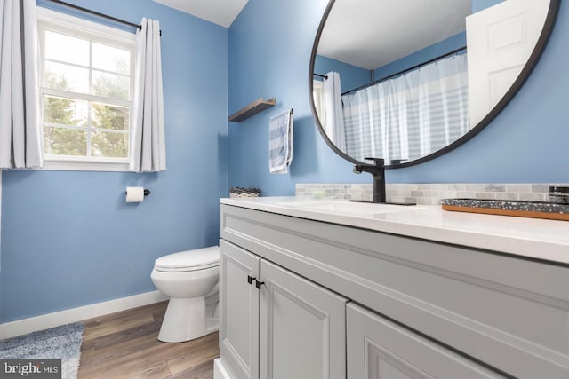 full bath with toilet, wood finished floors, decorative backsplash, baseboards, and vanity