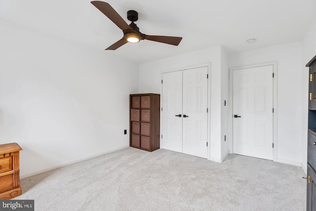 unfurnished bedroom with a closet, baseboards, a ceiling fan, and carpet flooring