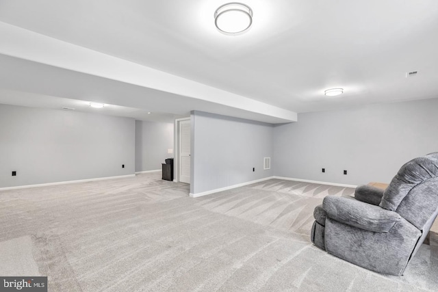 finished basement with visible vents, light colored carpet, and baseboards