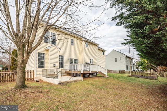 rear view of house featuring a deck, a lawn, and a fenced backyard