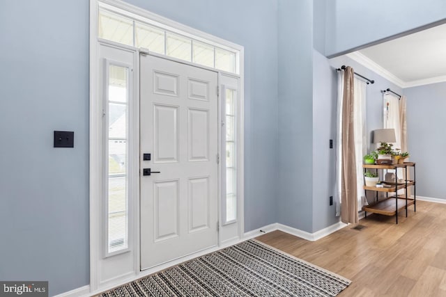 entryway with light wood-style flooring, plenty of natural light, baseboards, and ornamental molding