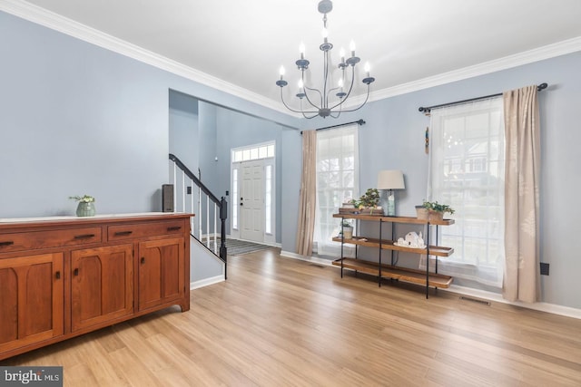 foyer with stairs, an inviting chandelier, light wood-style floors, and ornamental molding