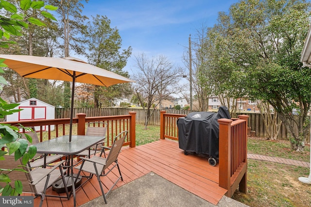 deck featuring a storage unit, an outbuilding, a grill, and a fenced backyard