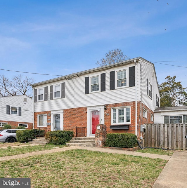 townhome / multi-family property featuring a front lawn, fence, and brick siding