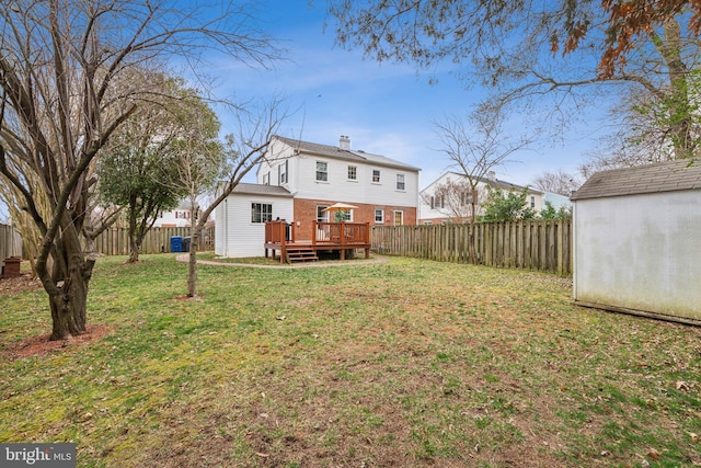 view of yard featuring a deck, an outdoor structure, a fenced backyard, and a storage shed