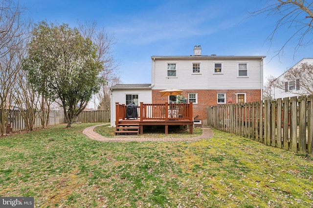 rear view of house featuring a wooden deck, brick siding, a fenced backyard, and a lawn