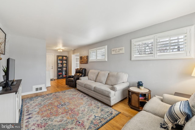 living area featuring visible vents, baseboards, and light wood-style floors