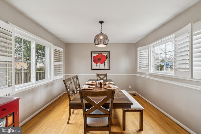 dining area with light wood-style flooring, baseboards, and a wealth of natural light