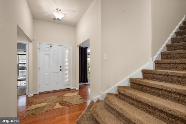 foyer with stairway, baseboards, visible vents, and wood finished floors