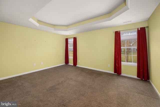 spare room featuring a tray ceiling, carpet flooring, baseboards, and visible vents