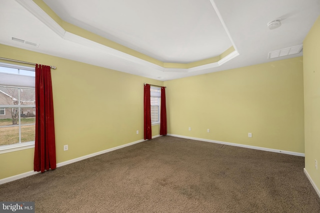 spare room featuring a tray ceiling, baseboards, and visible vents