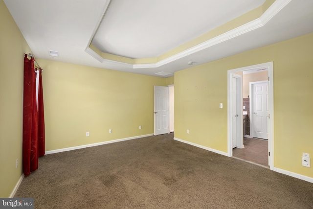 carpeted spare room with visible vents, baseboards, and a tray ceiling