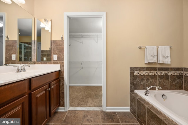 bathroom with vanity, a stall shower, a spacious closet, and a bath