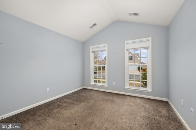 empty room featuring visible vents, baseboards, dark carpet, and vaulted ceiling