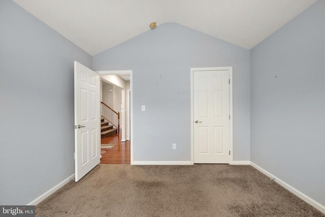 unfurnished bedroom featuring lofted ceiling, baseboards, and carpet floors