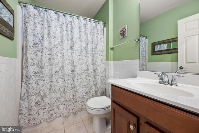 bathroom featuring a wainscoted wall, toilet, tile walls, tile patterned flooring, and vanity