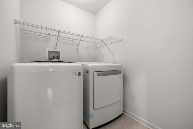 washroom featuring light tile patterned floors, baseboards, washing machine and dryer, and laundry area