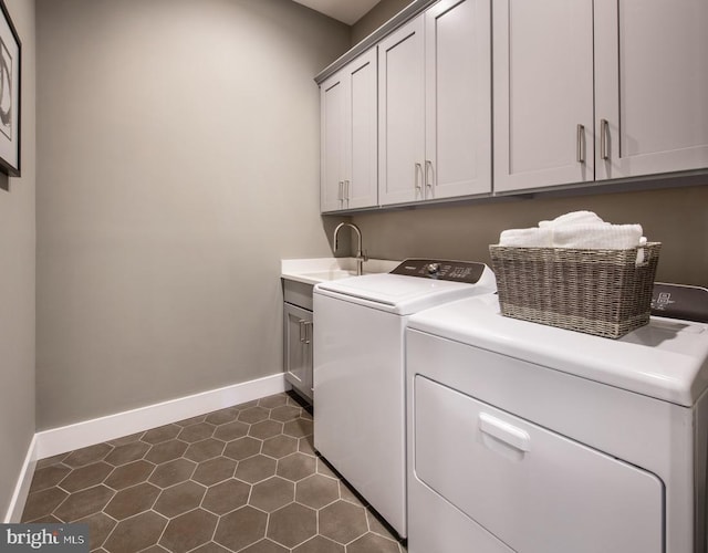 laundry area with baseboards, cabinet space, a sink, dark tile patterned floors, and washer and clothes dryer