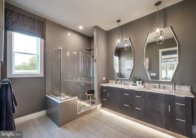 full bathroom featuring a sink, wood finished floors, a shower stall, double vanity, and baseboards