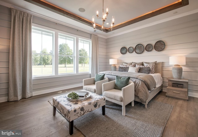 bedroom featuring a tray ceiling, a notable chandelier, and wood finished floors