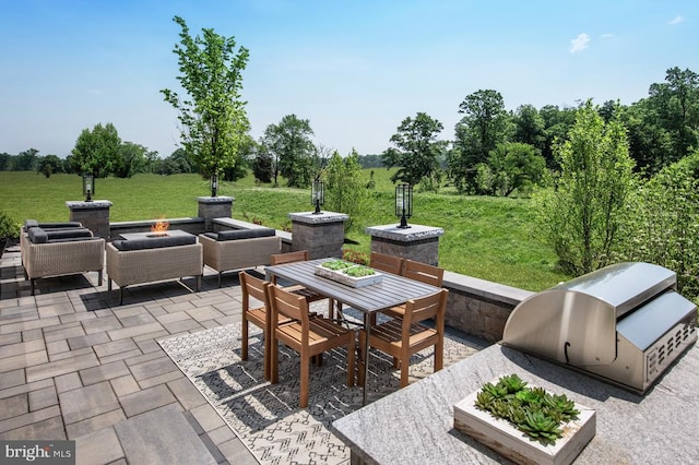 view of patio featuring grilling area, exterior kitchen, outdoor dining space, and an outdoor fire pit