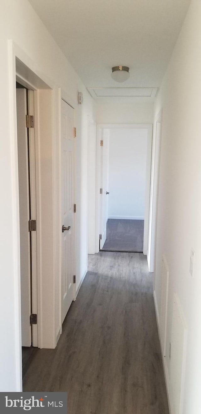 hallway with attic access and wood finished floors