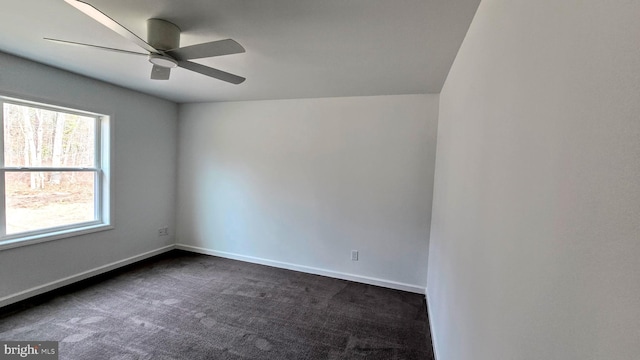 empty room with dark colored carpet, baseboards, and a ceiling fan