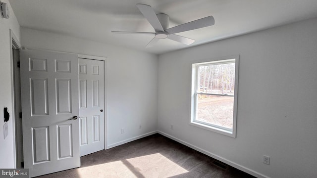 unfurnished bedroom with visible vents, a ceiling fan, dark carpet, a closet, and baseboards