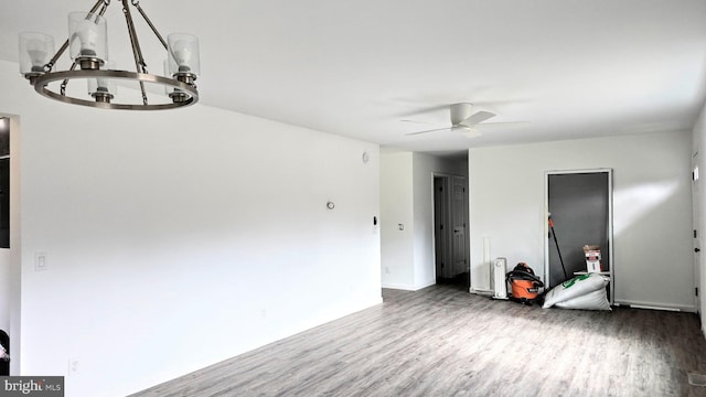 spare room featuring ceiling fan with notable chandelier and wood finished floors