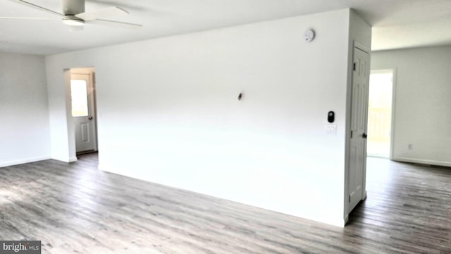 spare room featuring dark wood finished floors, baseboards, and a ceiling fan