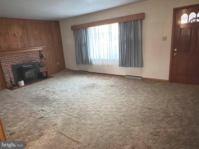unfurnished living room with plenty of natural light, carpet, visible vents, and wood walls