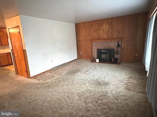 unfurnished living room with visible vents, light colored carpet, and wood walls