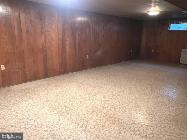finished basement with tile patterned floors and wood walls