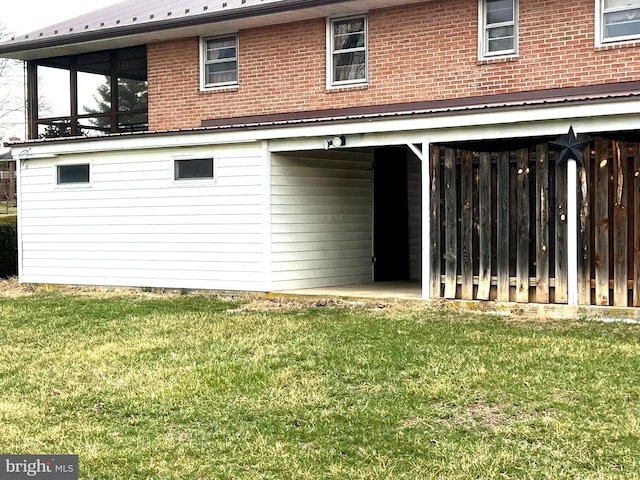 back of property featuring brick siding, a lawn, and metal roof