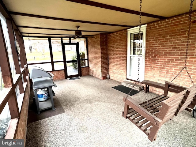 sunroom / solarium featuring beam ceiling and ceiling fan