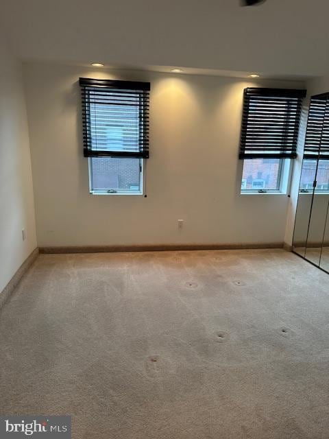 spare room with light colored carpet and baseboards