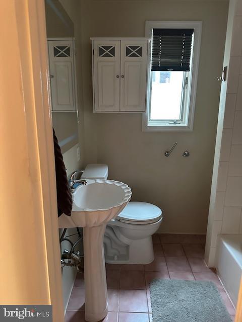 bathroom with tile patterned flooring, toilet, a bathing tub, and walk in shower